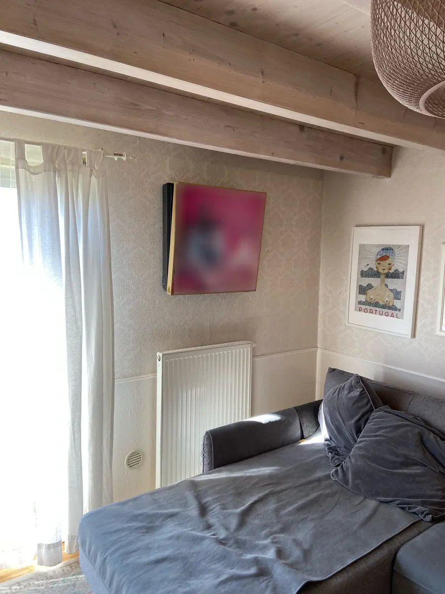LG Klimagerät im Bilderrahmen-Design an einer tapezierten Wand unter einer Holzbalkendecke