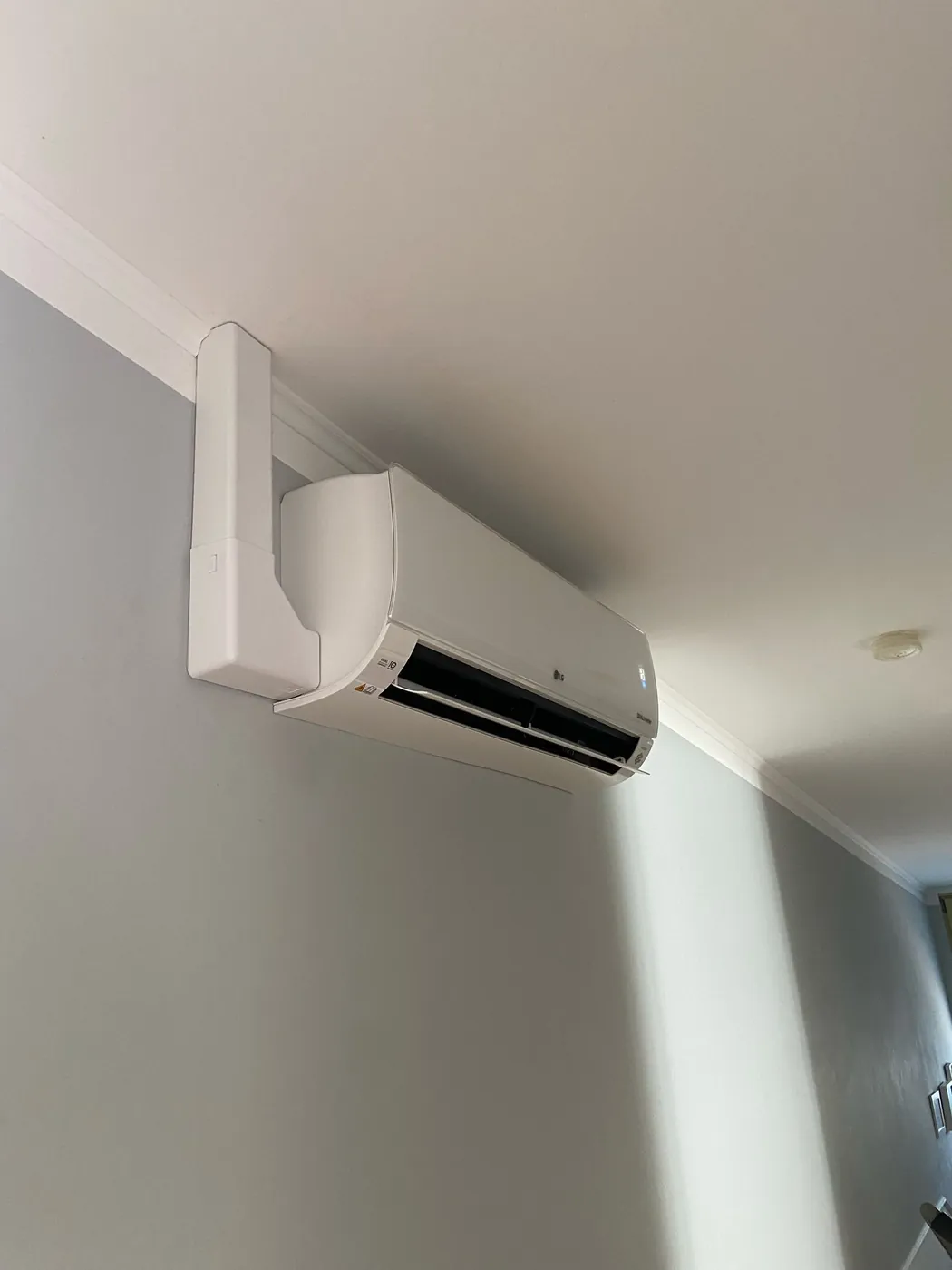 LG Wandgerät mit weißem Leitungskanal entlang der Deckenleiste
