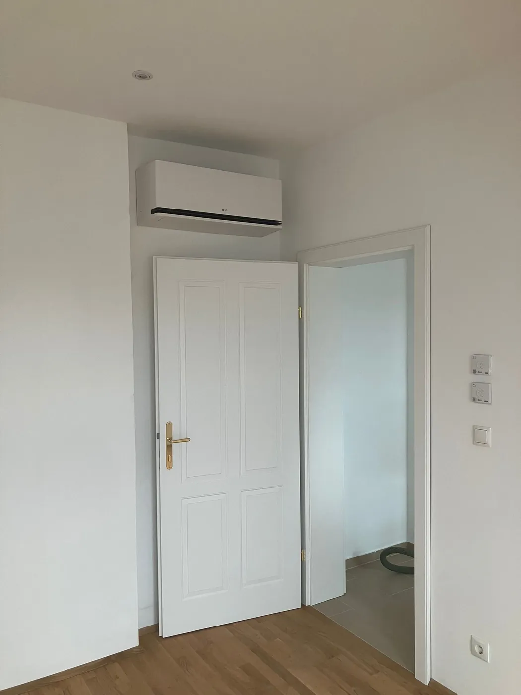 LG Wandgerät über einer weißen Kassettentür in einem hellen Zimmer