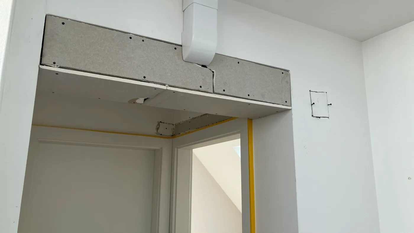 Kältemittelleitungen verschwinden in einer Trockenbau-Verkleidung über einer Tür, noch vor dem Spachteln