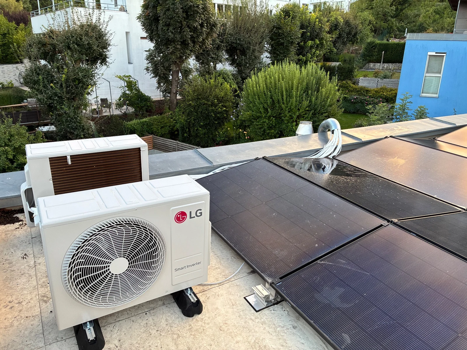 LG Außengerät einer Klimaanlage auf einem Flachdach neben Solarpaneelen